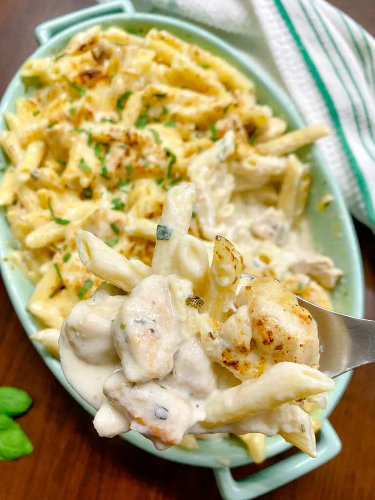 chicken alfredo bake in a blue baking dish garnished with parsley