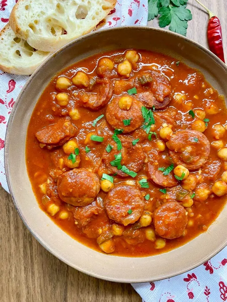 chorizo chickpea stew in a brown bowl garnished with parsley