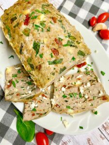 Mediterranean turkey meatloaf on a white plate with feta and parsley