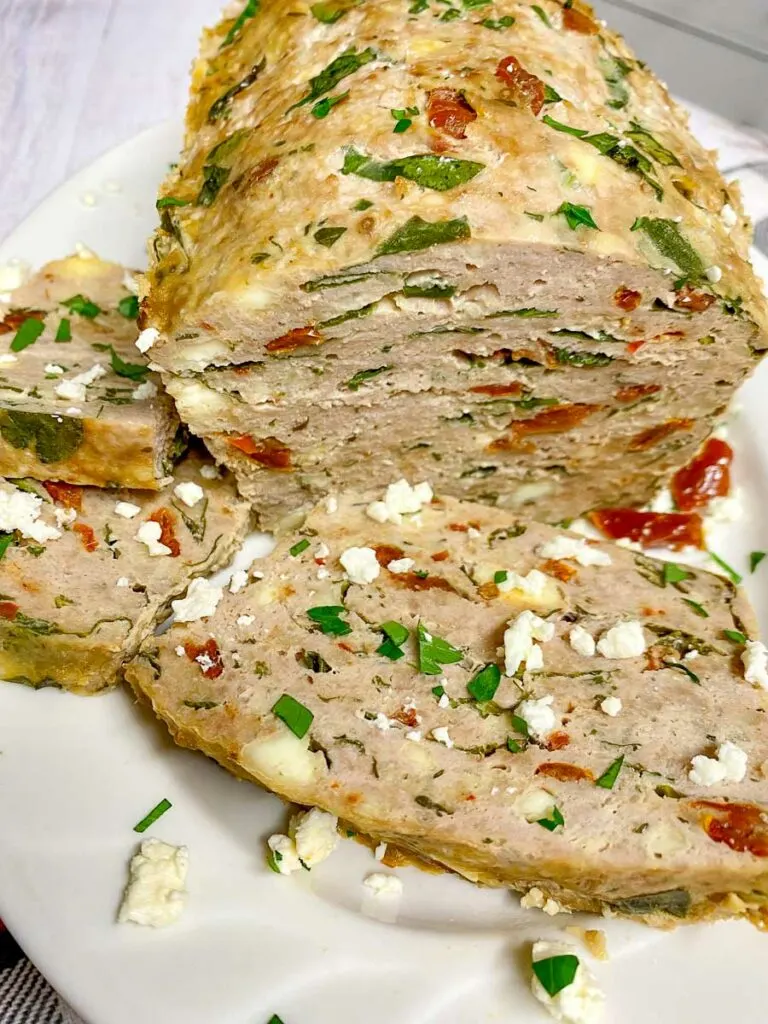 Mediterranean turkey meatloaf on a white plate with feta and parsley