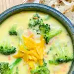 bowl of broccoli cheddar soup with a side of baguette