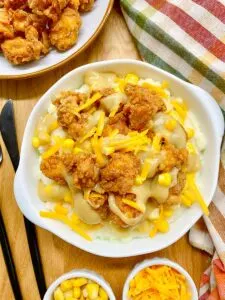 copycat KFC famous bowl served in a white bowl with mashed potatoes, corn, cheddar cheese, gravy and popcorn chicken