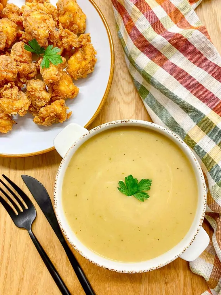 copycat KFC gravy in a white bowl with a side of popcorn chicken