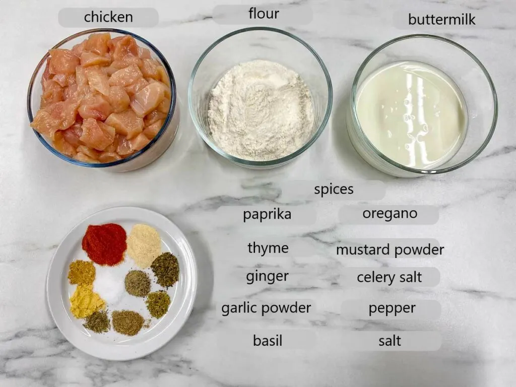 bowls with chicken, flour, buttermilk and spices. the ingredients to make copycat kfc popcorn chicken