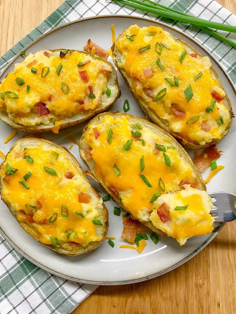 loaded twice baked potatoes on a gray plate garnished with green onions