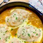 French onion chicken in a cast iron skillet garnished with parsley