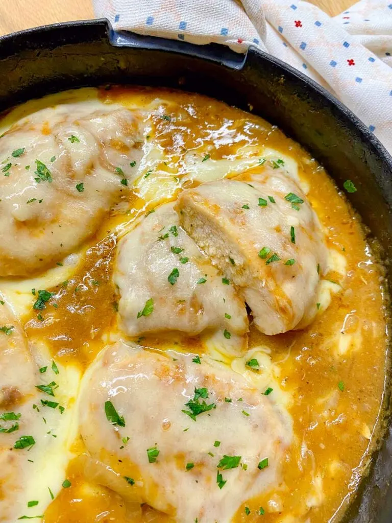 French onion chicken in a cast iron skillet garnished with parsley