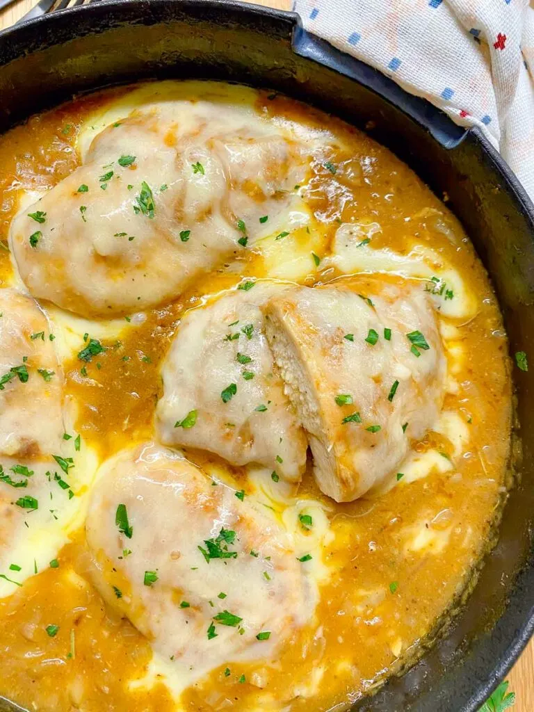 French onion chicken in a cast iron skillet garnished with parsley