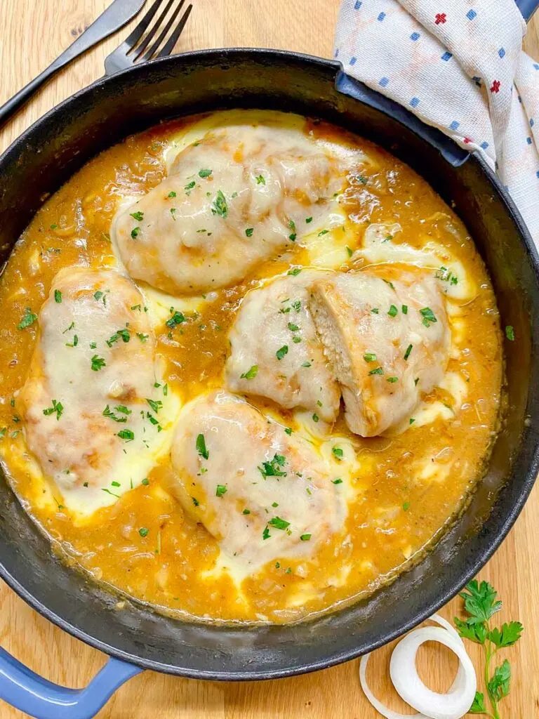 French onion chicken in a cast iron skillet garnished with parsley