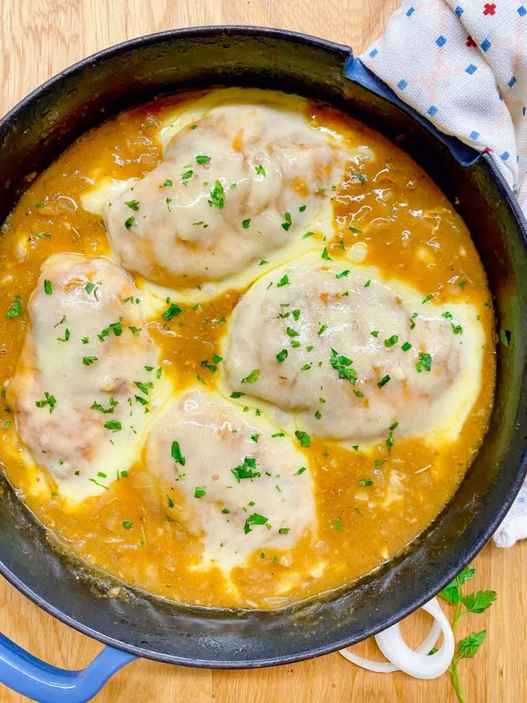 French onion chicken in a cast iron skillet garnished with parsley