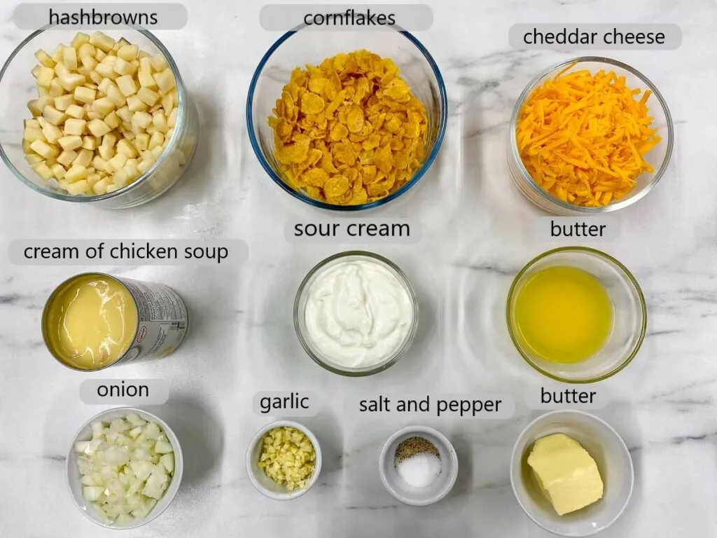 bowls with hashbrowns, cornflakes, cheddar cheese, cream of chicken soup, sour cream, butter, onion, garlic, salt and pepper. the ingredients to make funeral potatoes