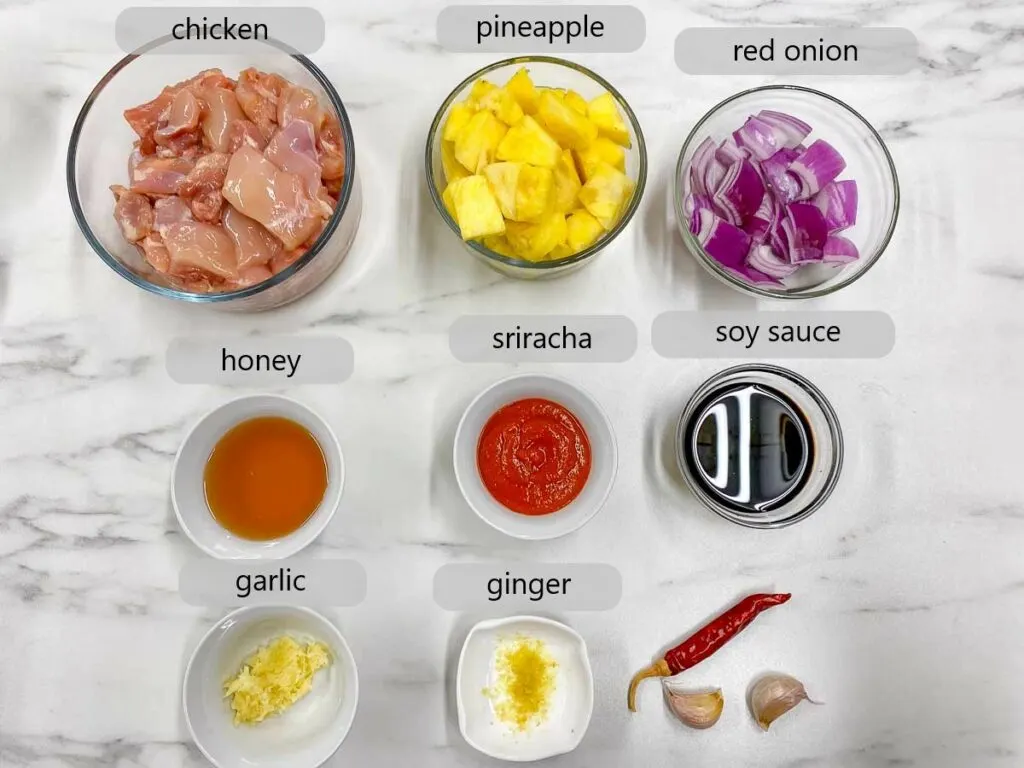 bowls with chicken, pineapple, red onion, honey, sriracha, soy sauce, garlic, and ginger. the ingredients to make honey sriracha pineapple chicken skewers