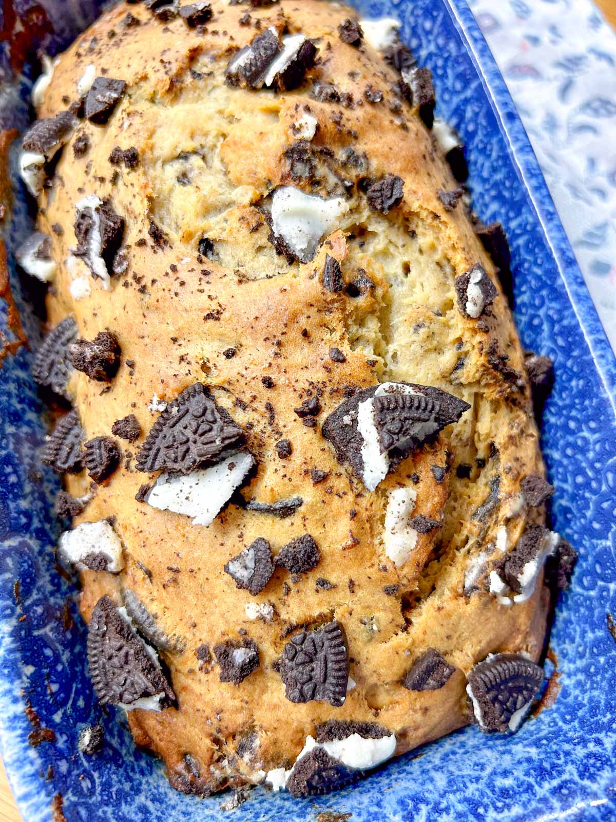 a loaf of Oreo banana bread is in a blue loaf pan.