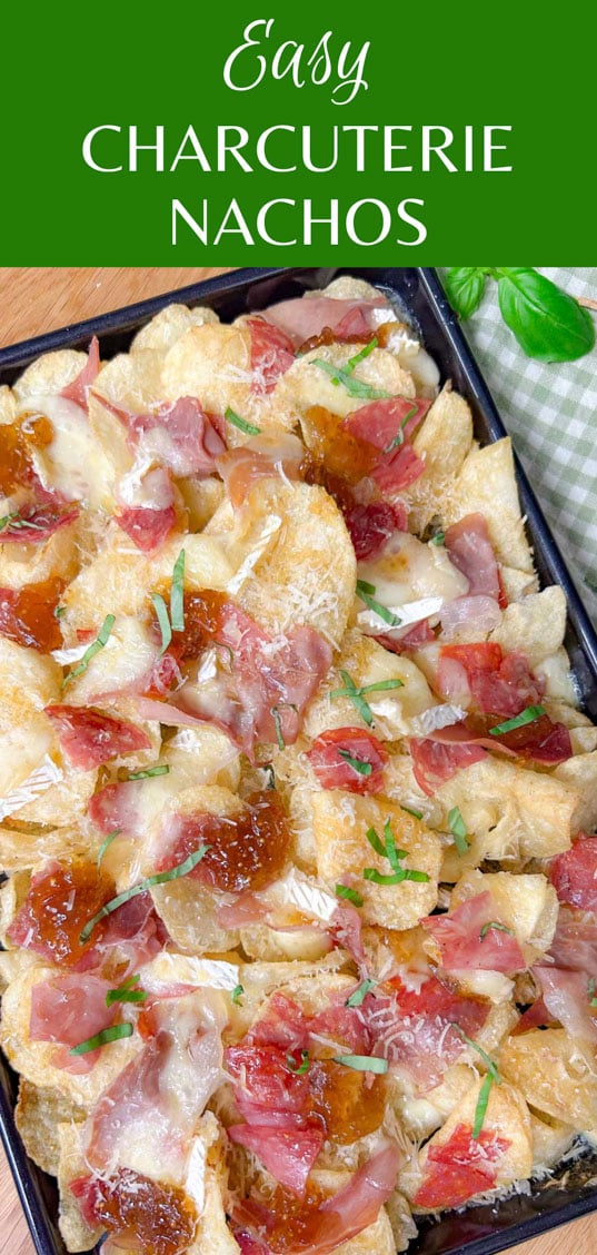 a black rimmed sheet pan is filled with baked charcuterie nachos and garnished with parmesan cheese and sliced basil. text overlay has the recipe name 'easy charcuterie nachos'