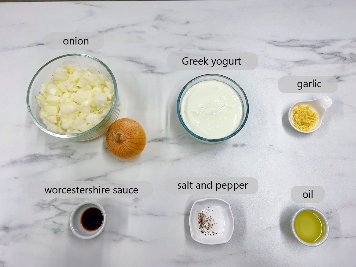 a white marble countertop has bowls with ingredients and text overlay reading onions, Greek yogurt, garlic, Worcestershire sauce, salt and pepper, and oil.