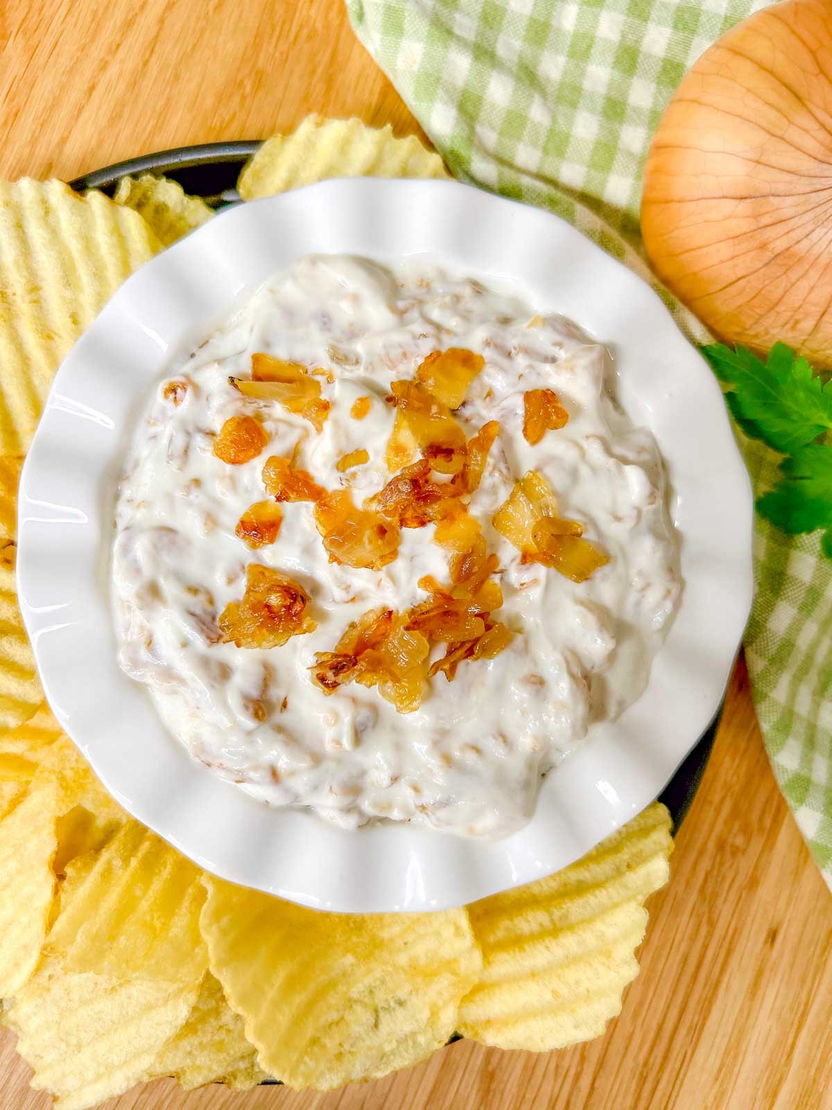 a white bowl is filled with French onion dip and garnished with caramelized onions.