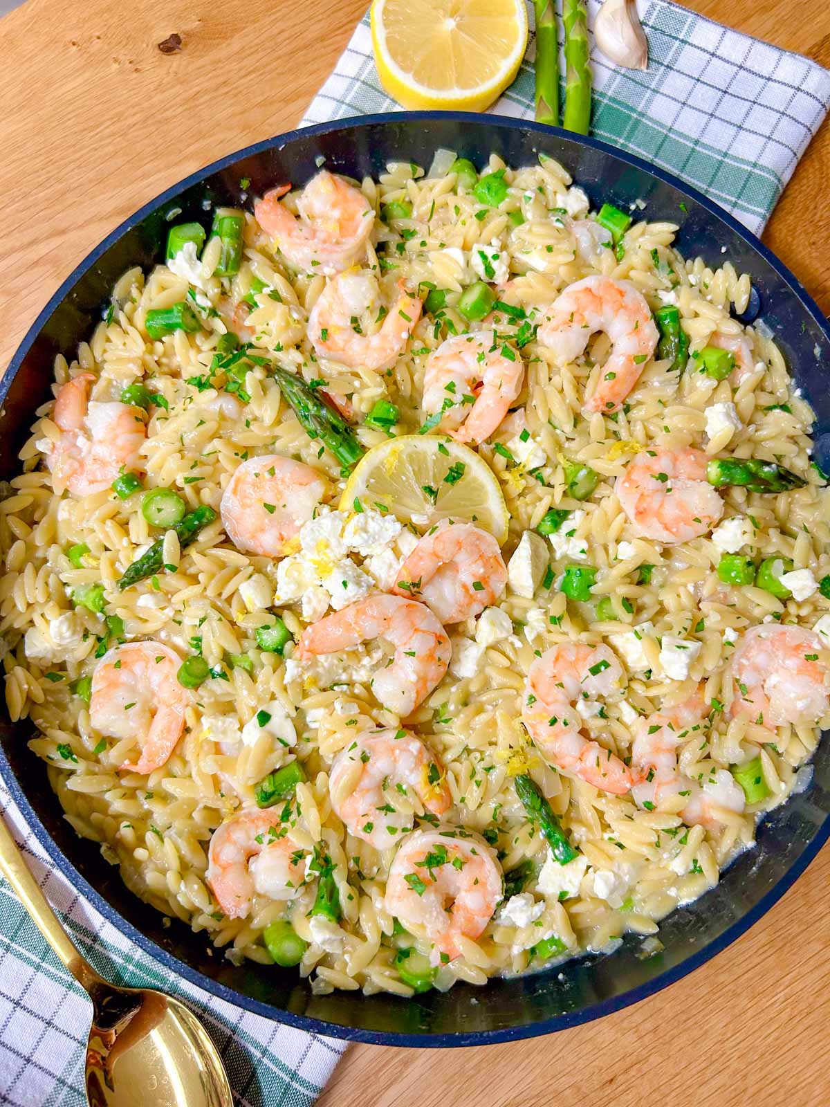 a black frying pan is filled with lemon feta shrimp orzo and garnished with parsley