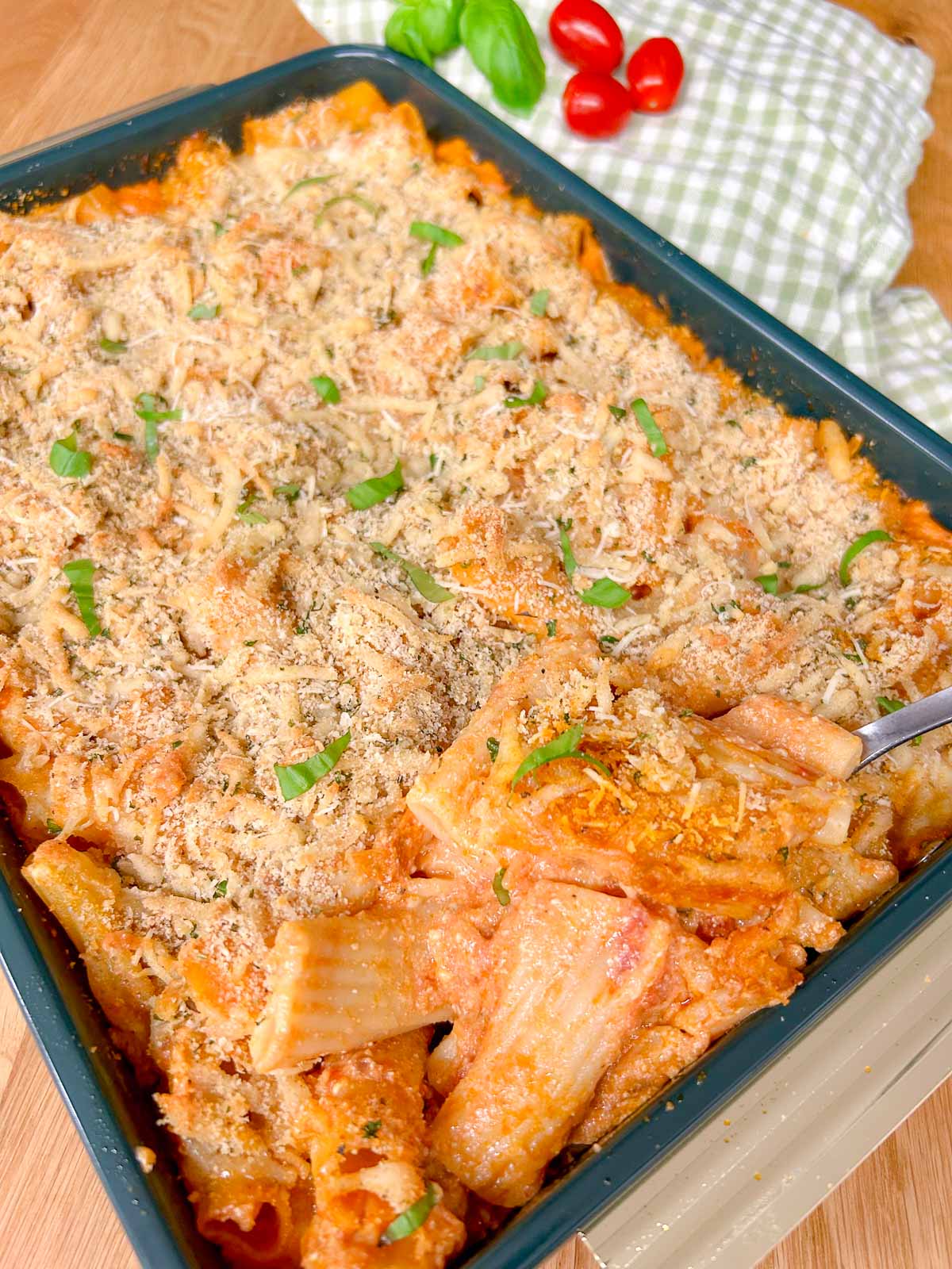 a baking tray has a five cheese ziti al forno baked into it and garnished with fresh basil.