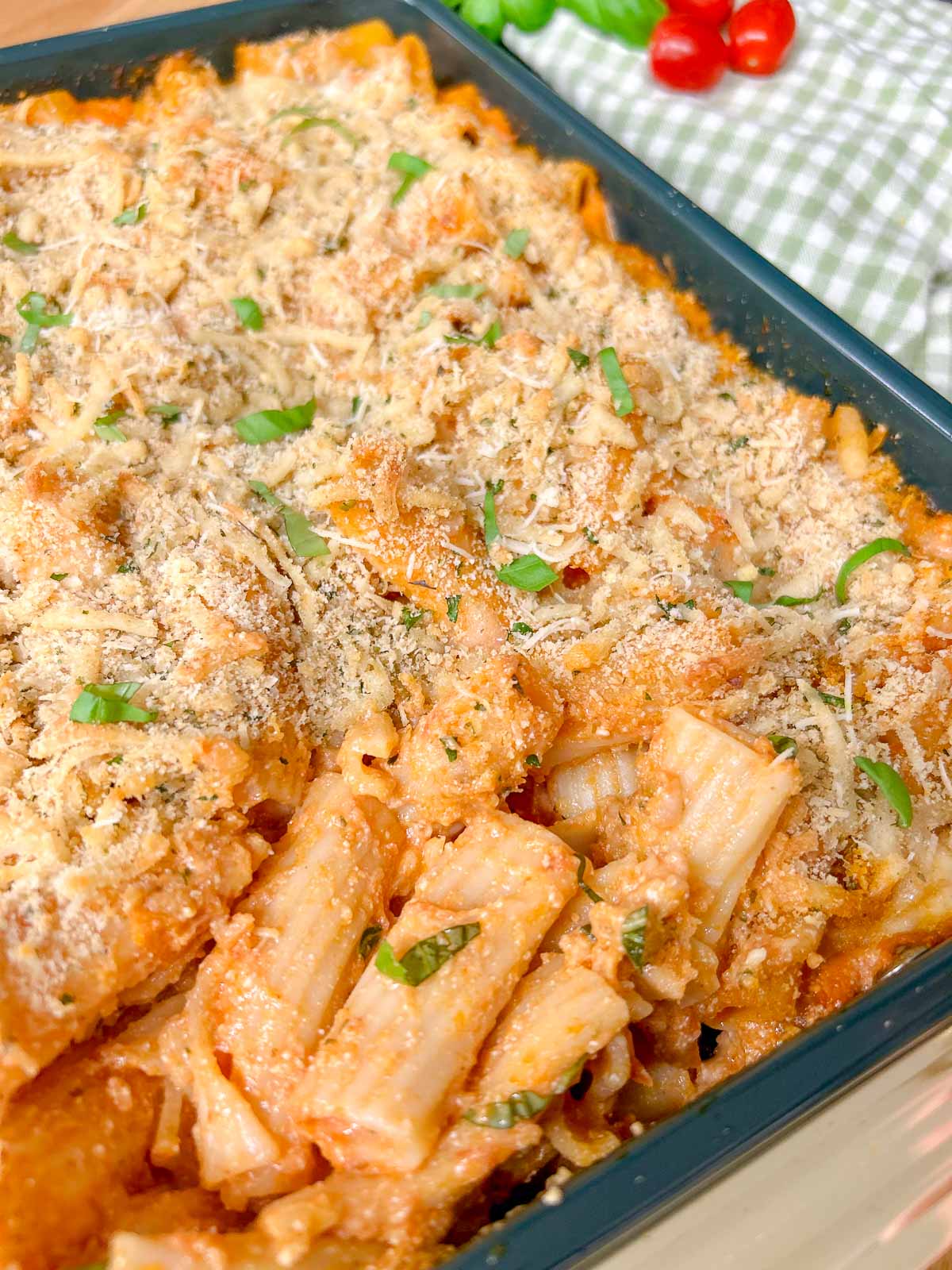 a baking tray has a five cheese ziti al forno baked into it and garnished with fresh basil.