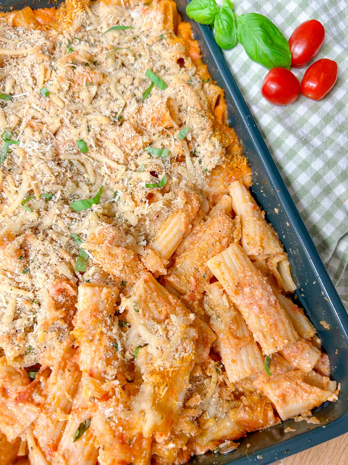 a baking tray has a five cheese ziti al forno baked into it and garnished with fresh basil.
