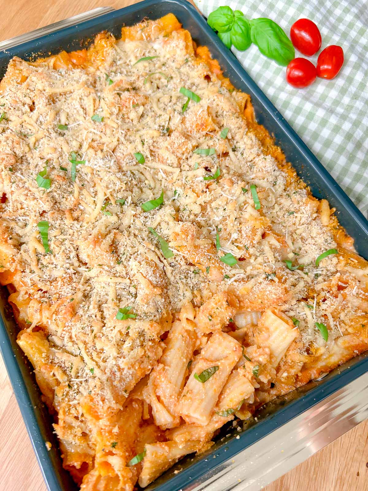a baking tray has a five cheese ziti al forno baked into it and garnished with fresh basil.