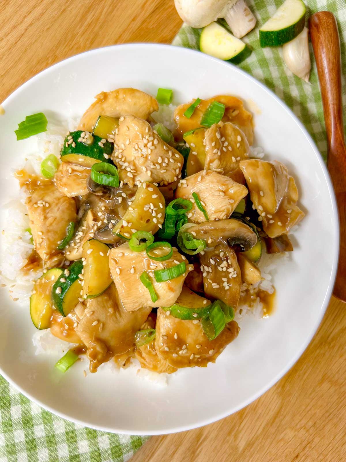 a white bowl is filled with Panda Express mushroom chicken copycat and garnished with sesame seeds and green onions