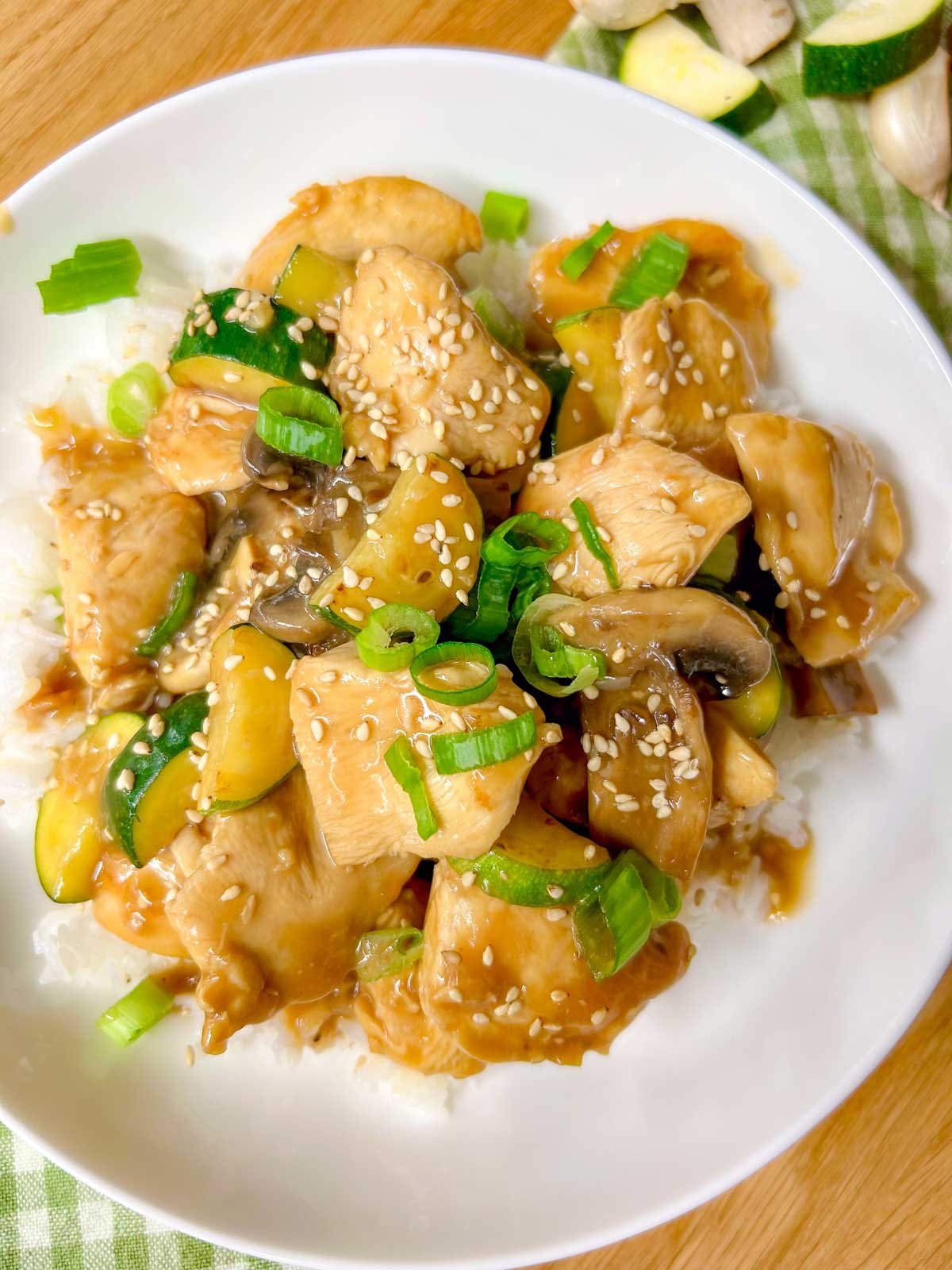 a white bowl is filled with Panda Express mushroom chicken copycat and garnished with sesame seeds and green onions