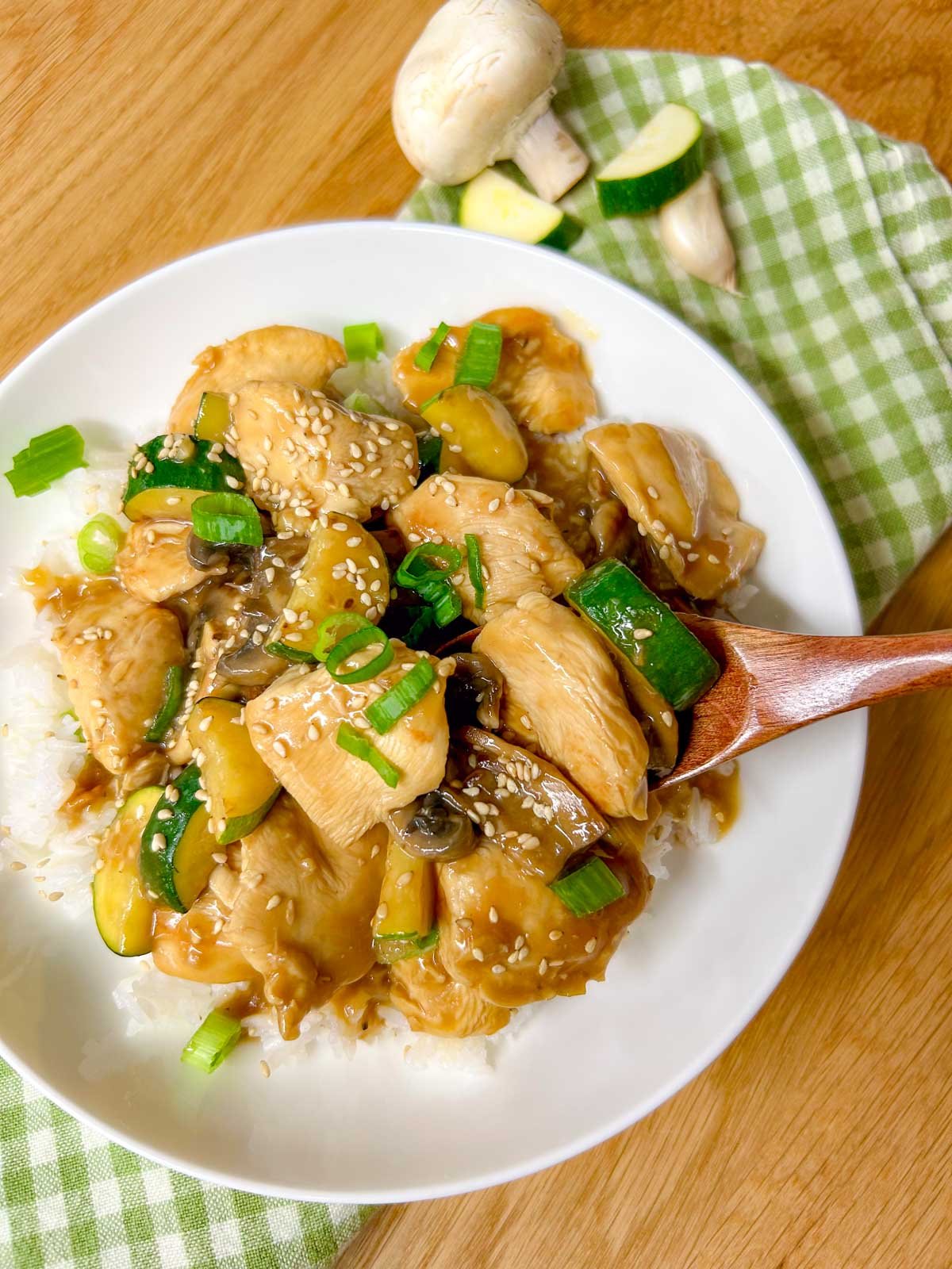 a white bowl is filled with Panda Express mushroom chicken copycat and garnished with sesame seeds and green onions