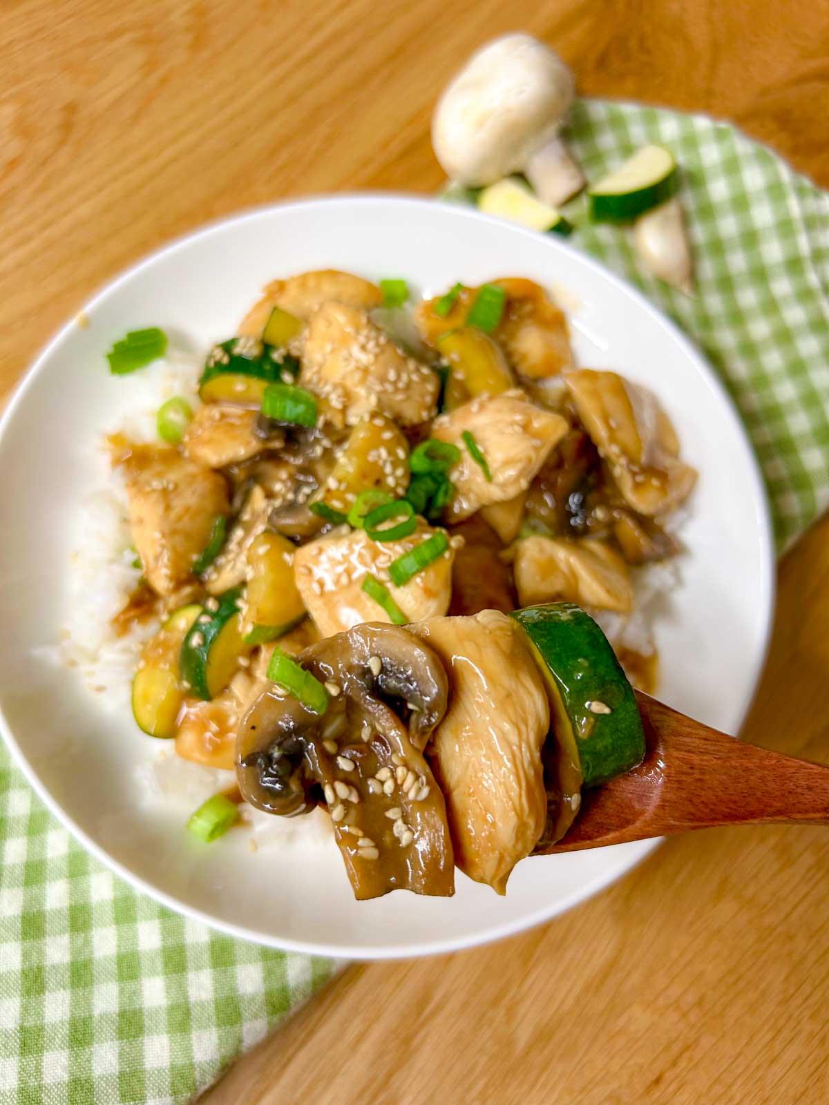 a white bowl is filled with Panda Express mushroom chicken copycat and garnished with sesame seeds and green onions