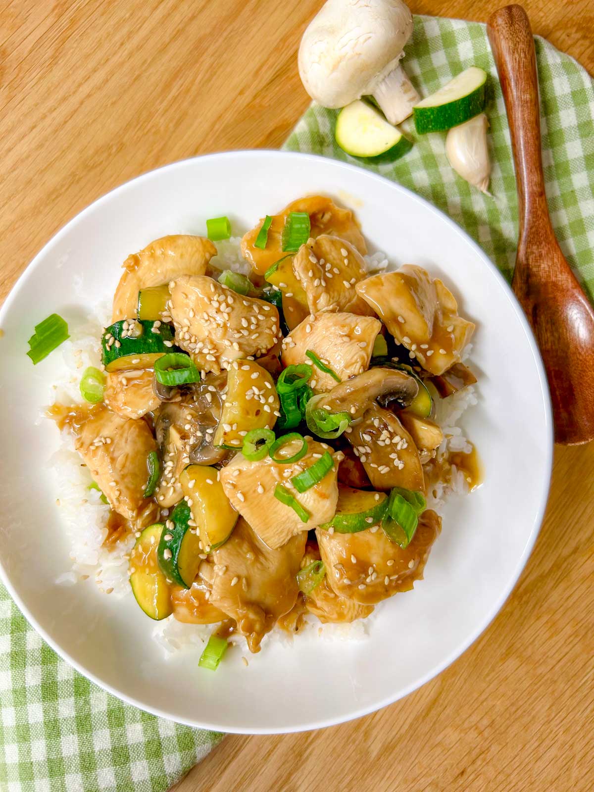 a white bowl is filled with Panda Express mushroom chicken copycat and garnished with sesame seeds and green onions