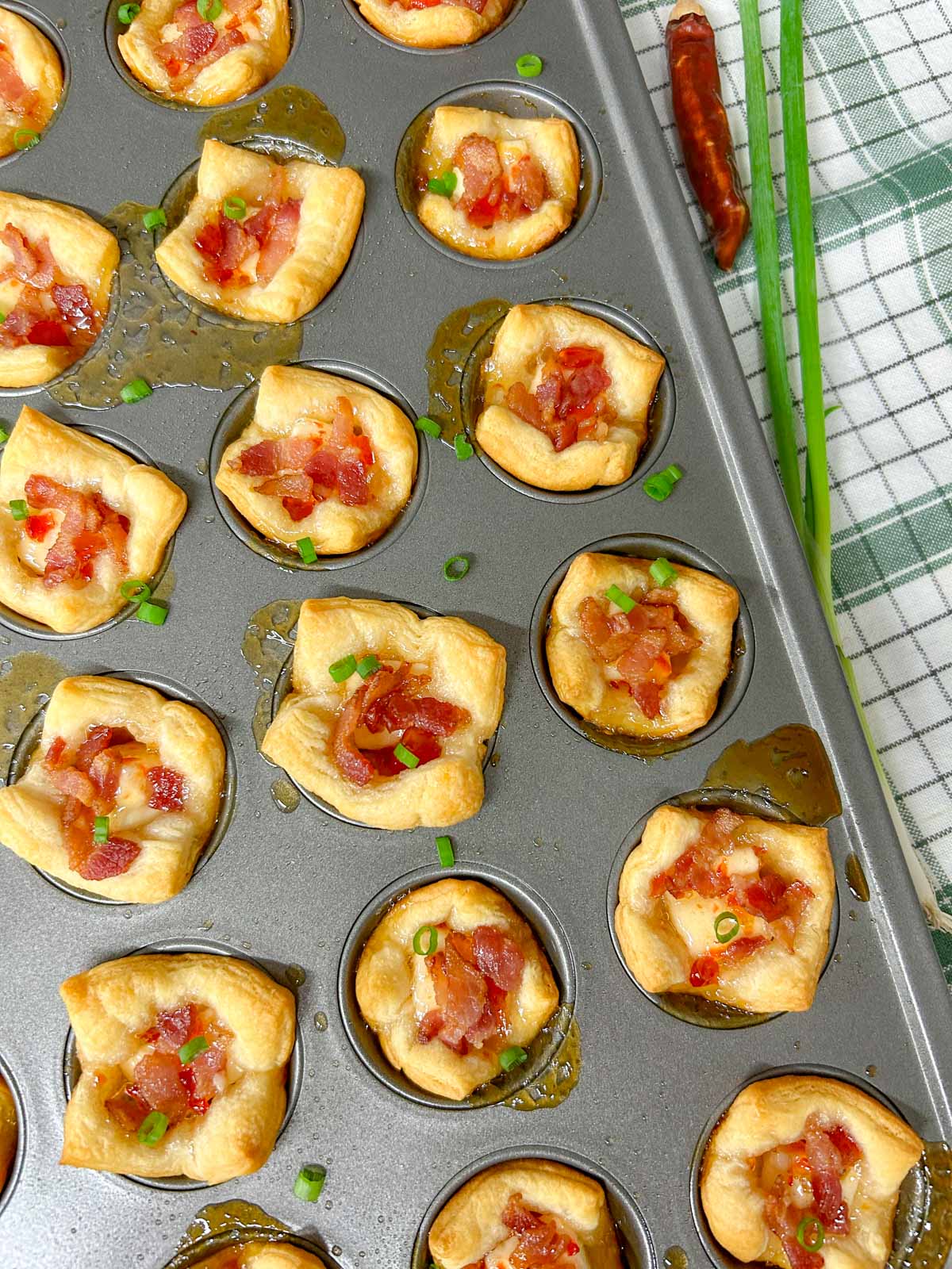 a mini muffin tin with bacon pepper jelly cheese cups inside