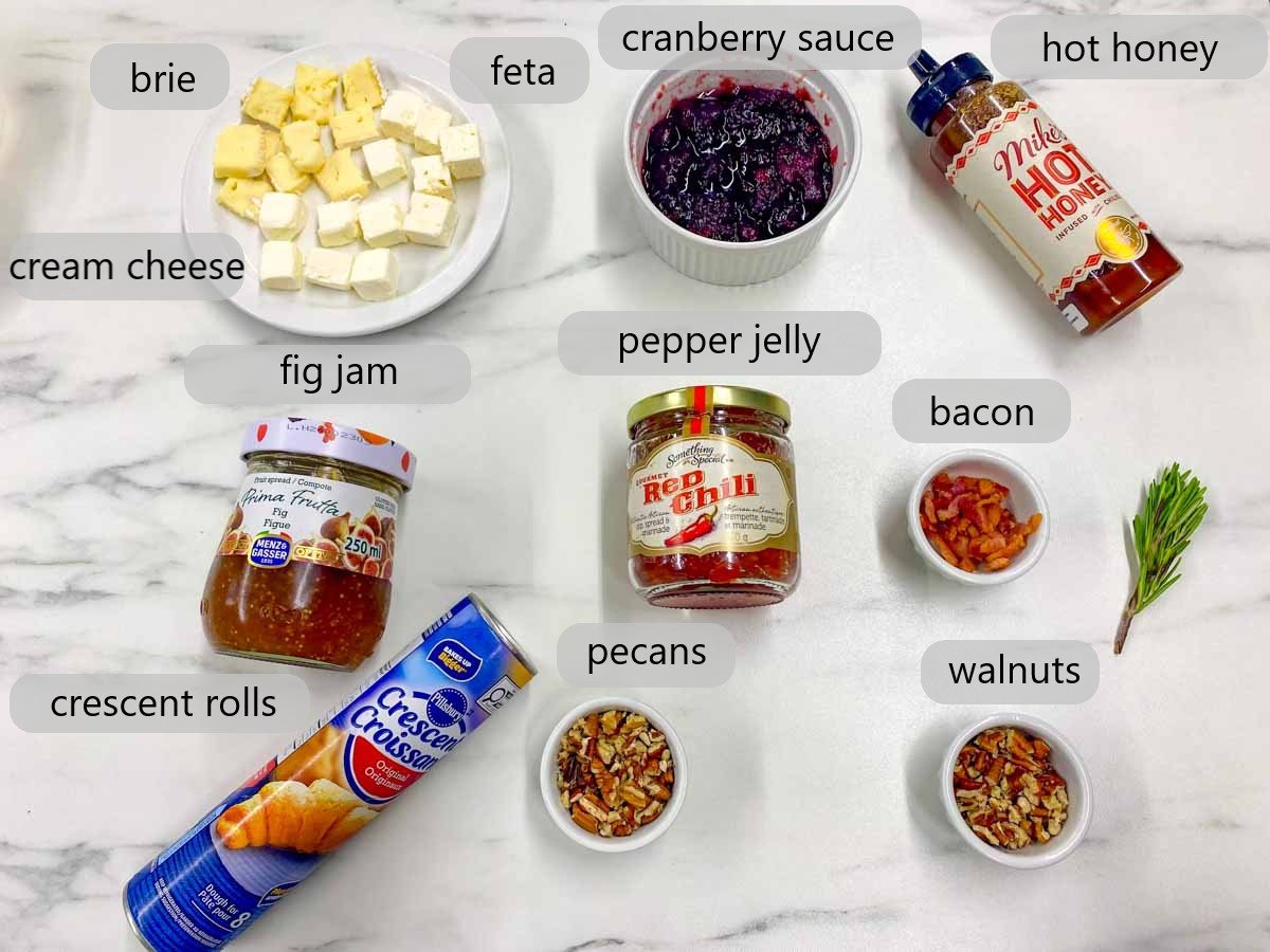 kitchen counter with ingredients and text overlays reading brie, feta, cream cheese, cranberry sauce, hot honey, fig jam, pepper jelly, bacon, crescent rolls, pecans and walnuts.