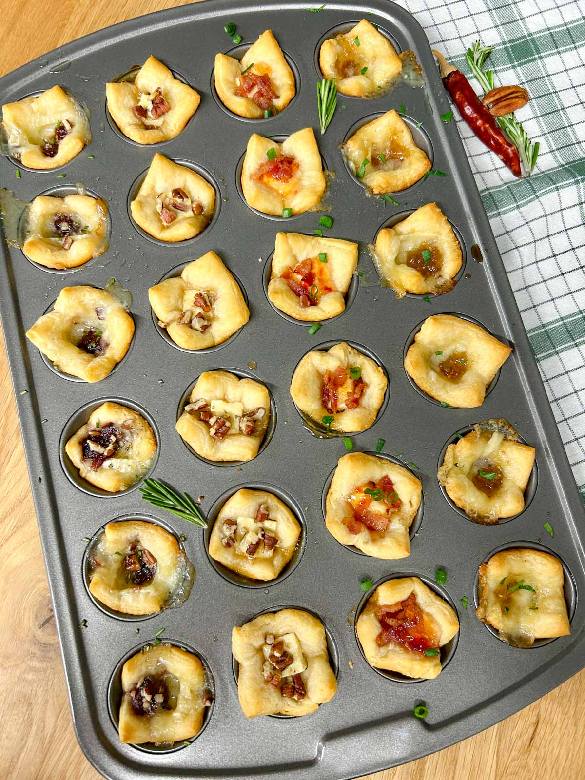 a muffin tin with 4 different flavors of baked cheese cups.