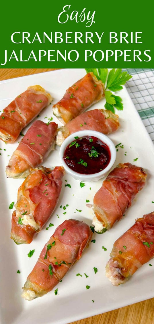 a white platter with  prosciutto wrapped cranberry brie jalapeno poppers garnished with chopped parsley.