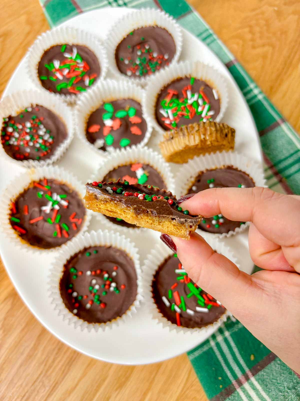  white platter is filled with Christmas crack cookies. one is held close to camera