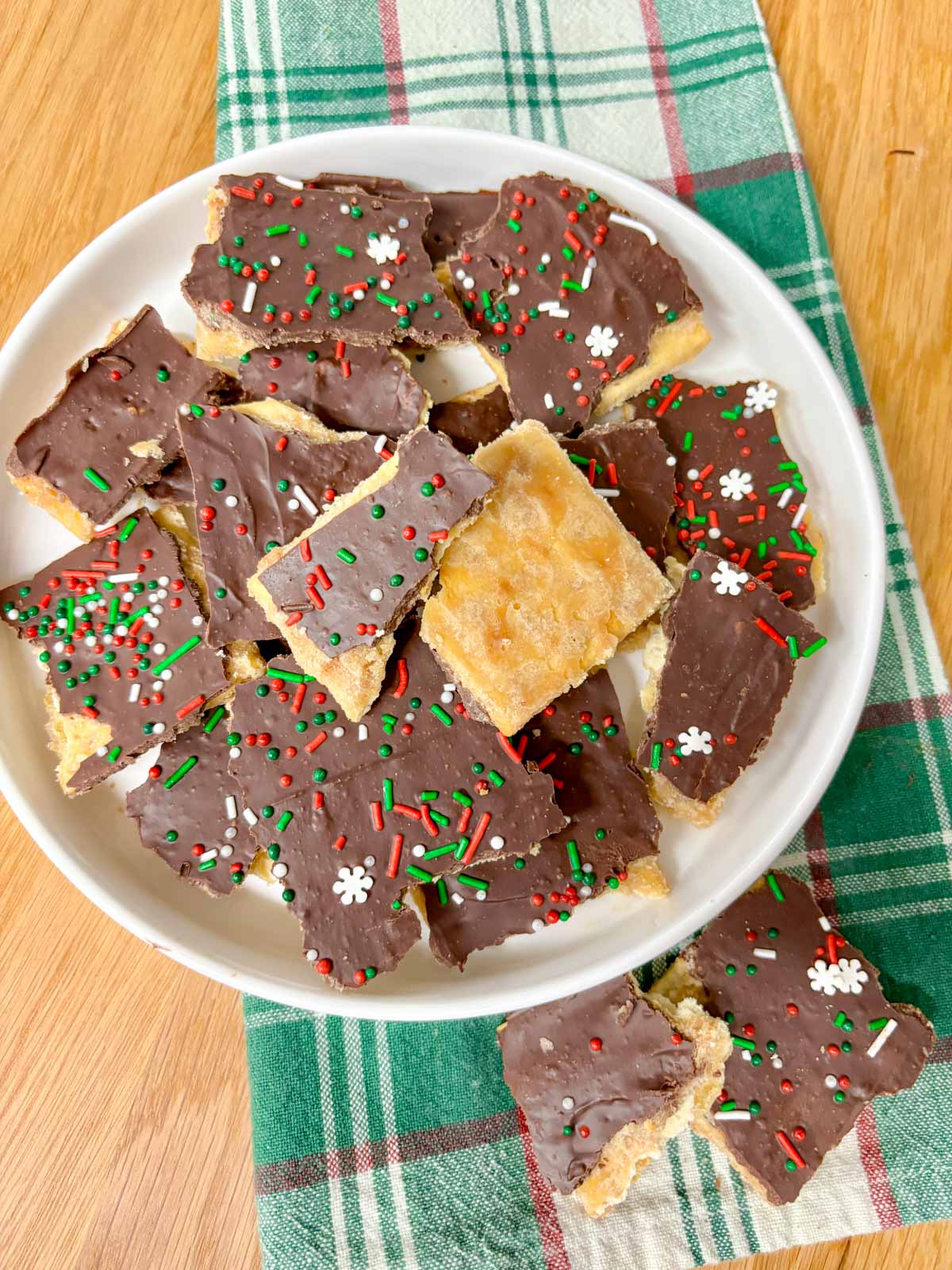 a round white bowl is filled with pieces of cracker toffee (Christmas crack).