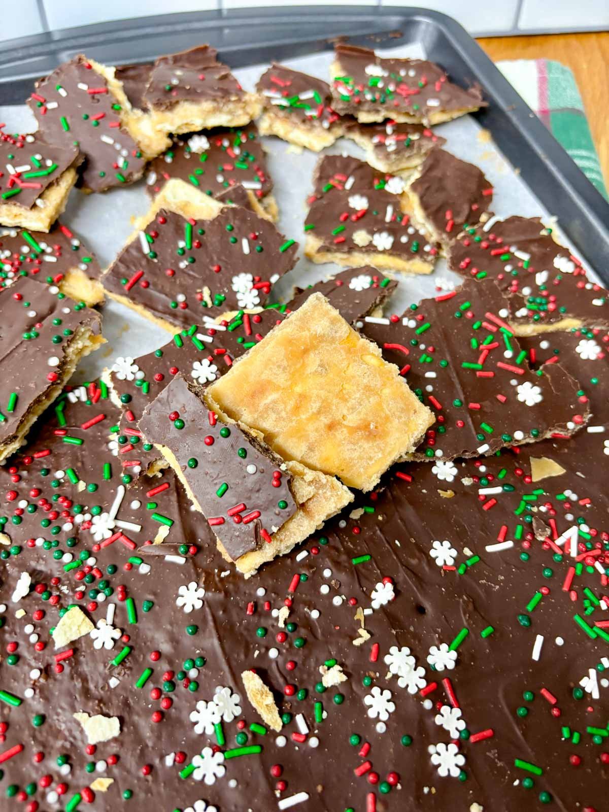a sheet pan is filled with pieces of cracker toffee (Christmas crack).