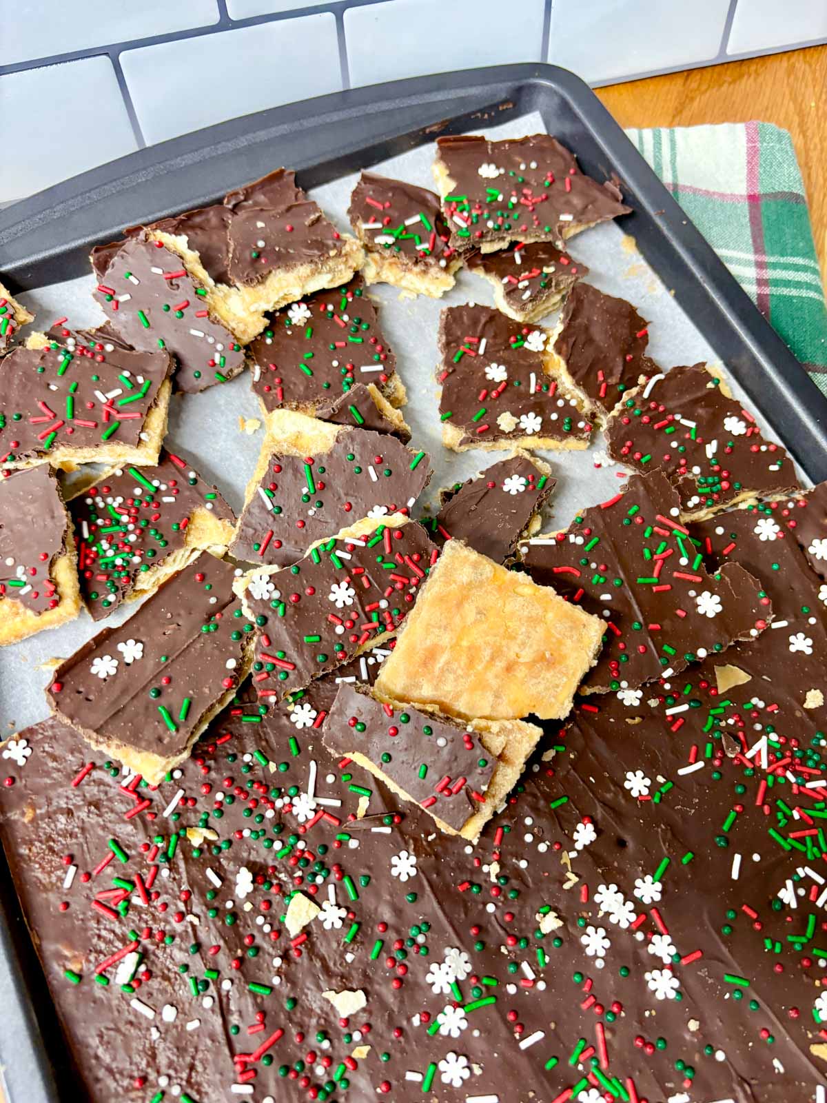 a sheet pan is filled with pieces of cracker toffee (Christmas crack).