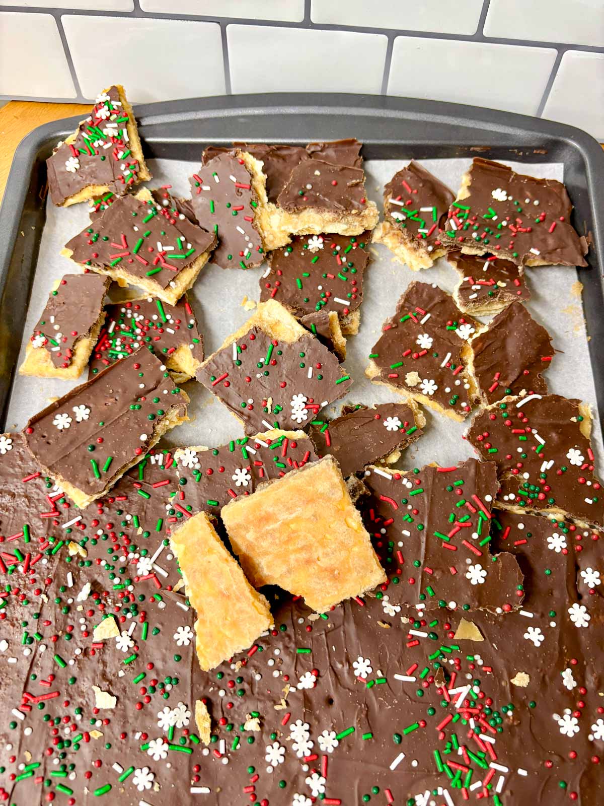a sheet pan is filled with pieces of cracker toffee (Christmas crack).