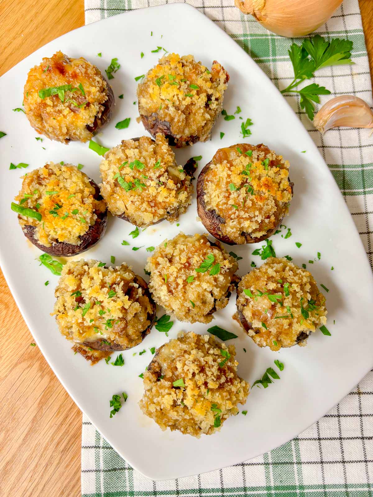 a white plate is filled with French onion stuffed mushrooms and garnished with parsley. 