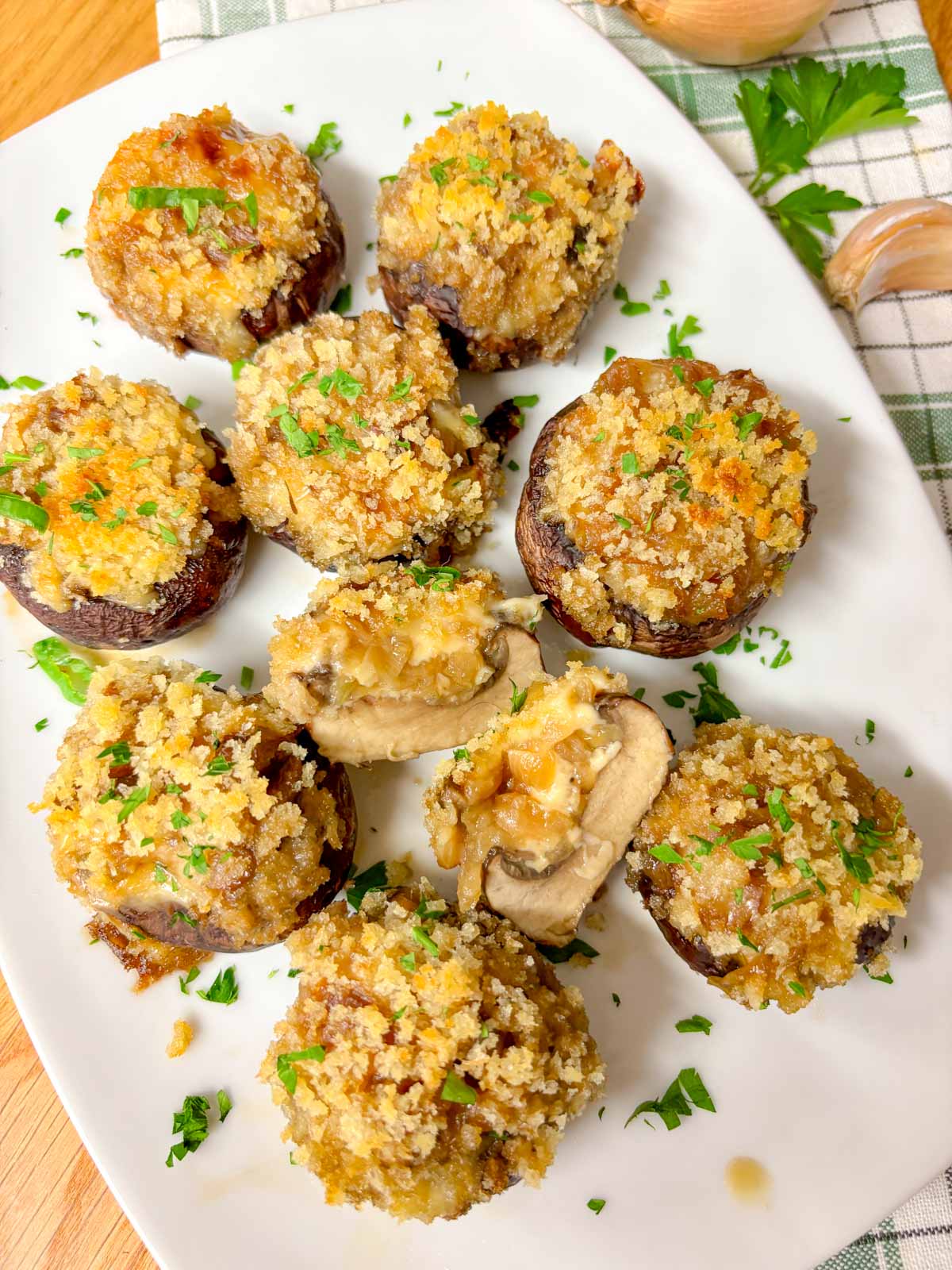 a white plate is filled with French onion stuffed mushrooms and garnished with parsley. one is sliced in half