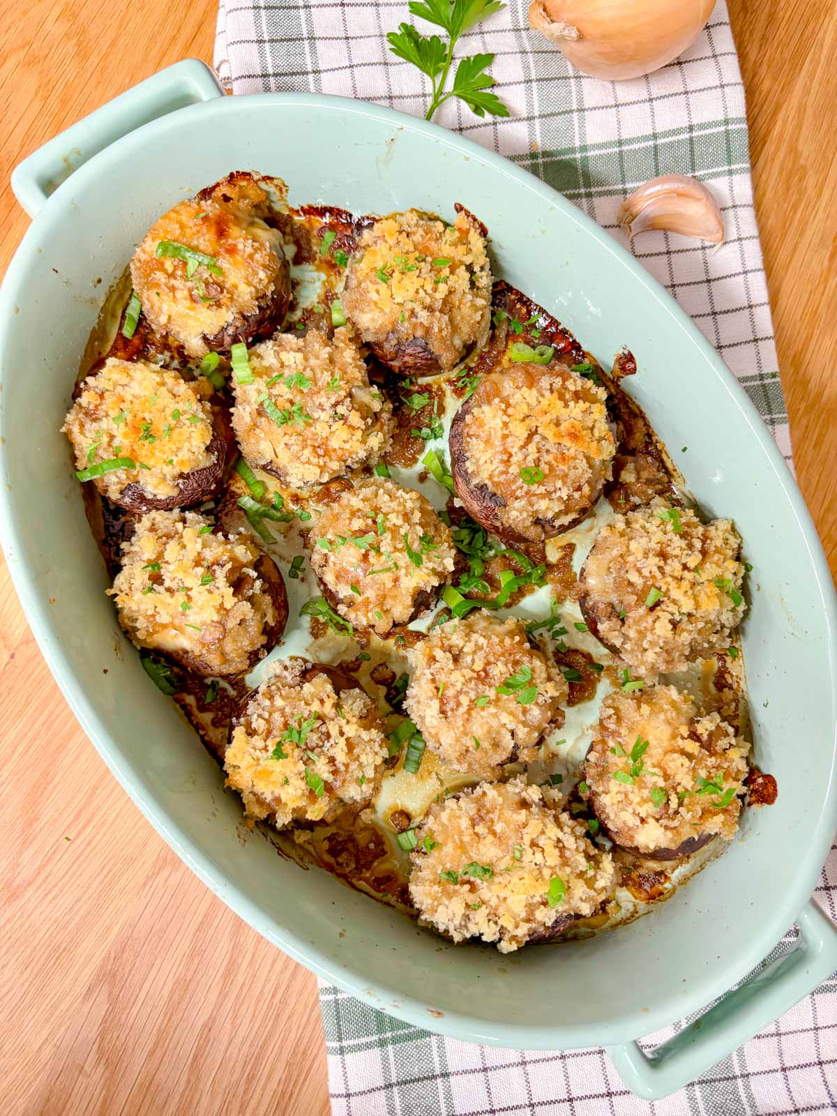 a blue baking tray is filled with French onion stuffed mushrooms and garnished with parsley. 