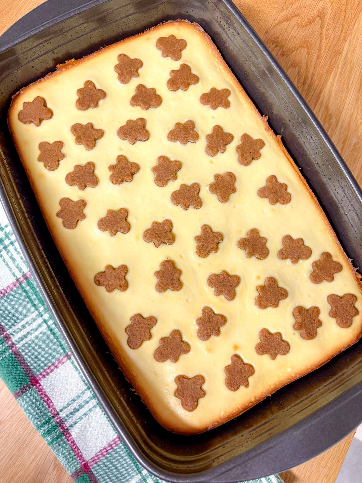 a rectangle baking tray is filled with a baked tray of gingerbread cheesecake bars