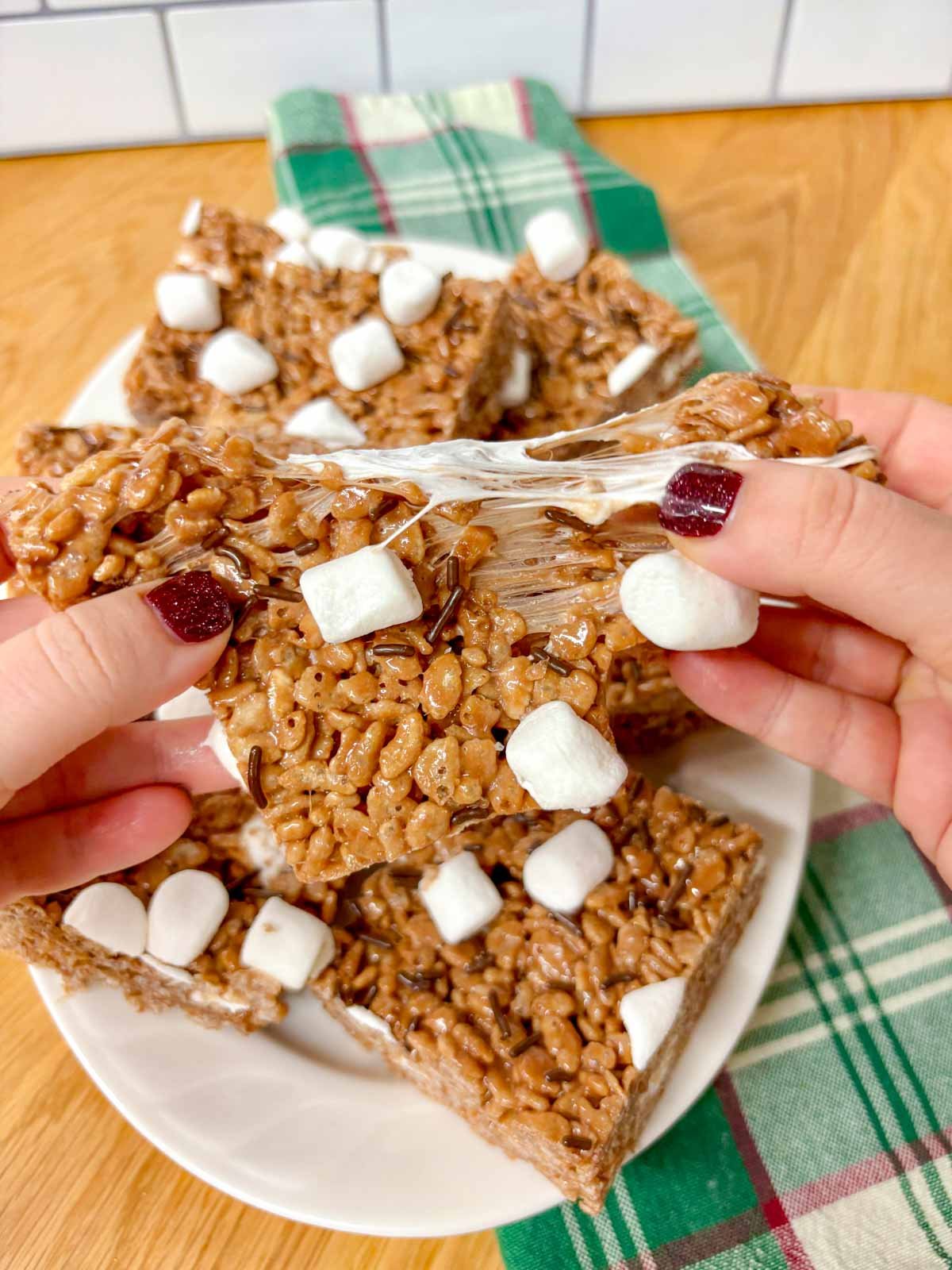 a white platter is filled with hot chocolate rice krispie treats. one is ripped in half