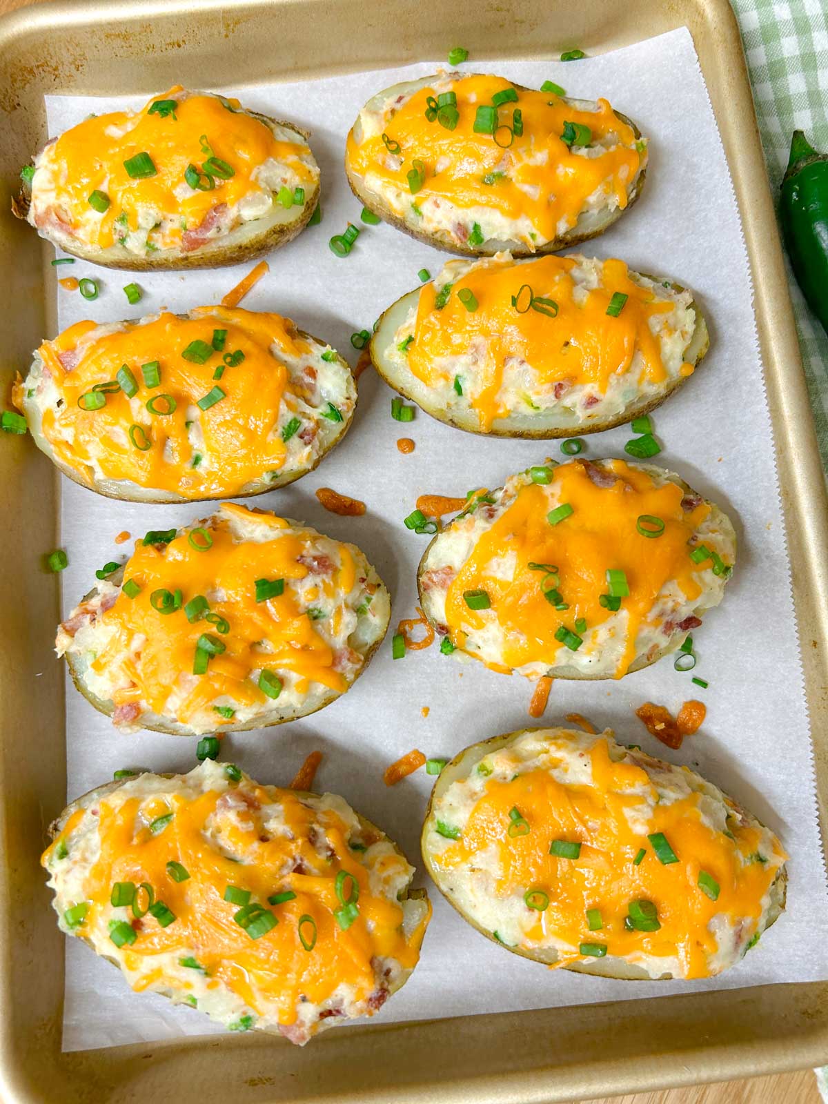a baking tray is filled with 8 jalapeno popper twice baked potatoes and garnished with green onions