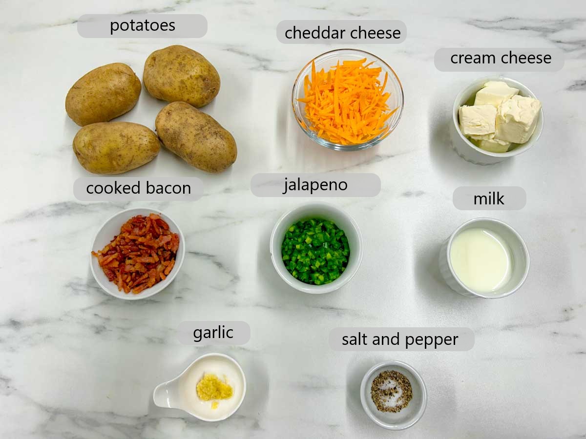 kitchen counter with bowls and ingredients with text overlays reading potatoes, cheddar cheese, cream cheese, cooked bacon, jalapeno, milk, garlic, salt and pepper.