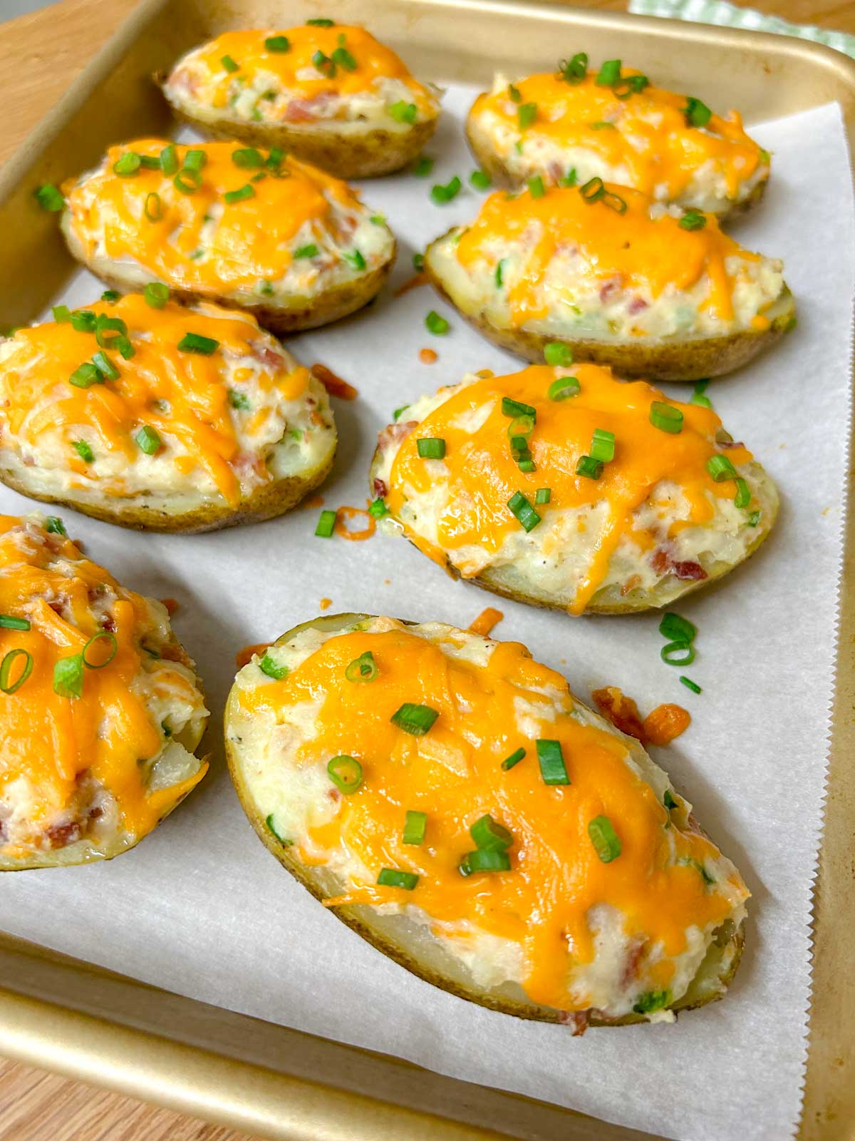 a baking tray is filled with 8 jalapeno popper twice baked potatoes and garnished with green onions