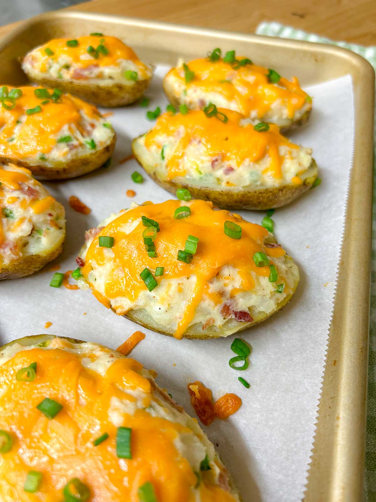 a baking tray is filled with 8 jalapeno popper twice baked potatoes and garnished with green onions