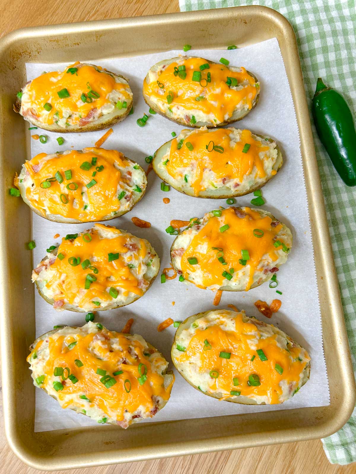 a baking tray is filled with 8 jalapeno popper twice baked potatoes and garnished with green onions