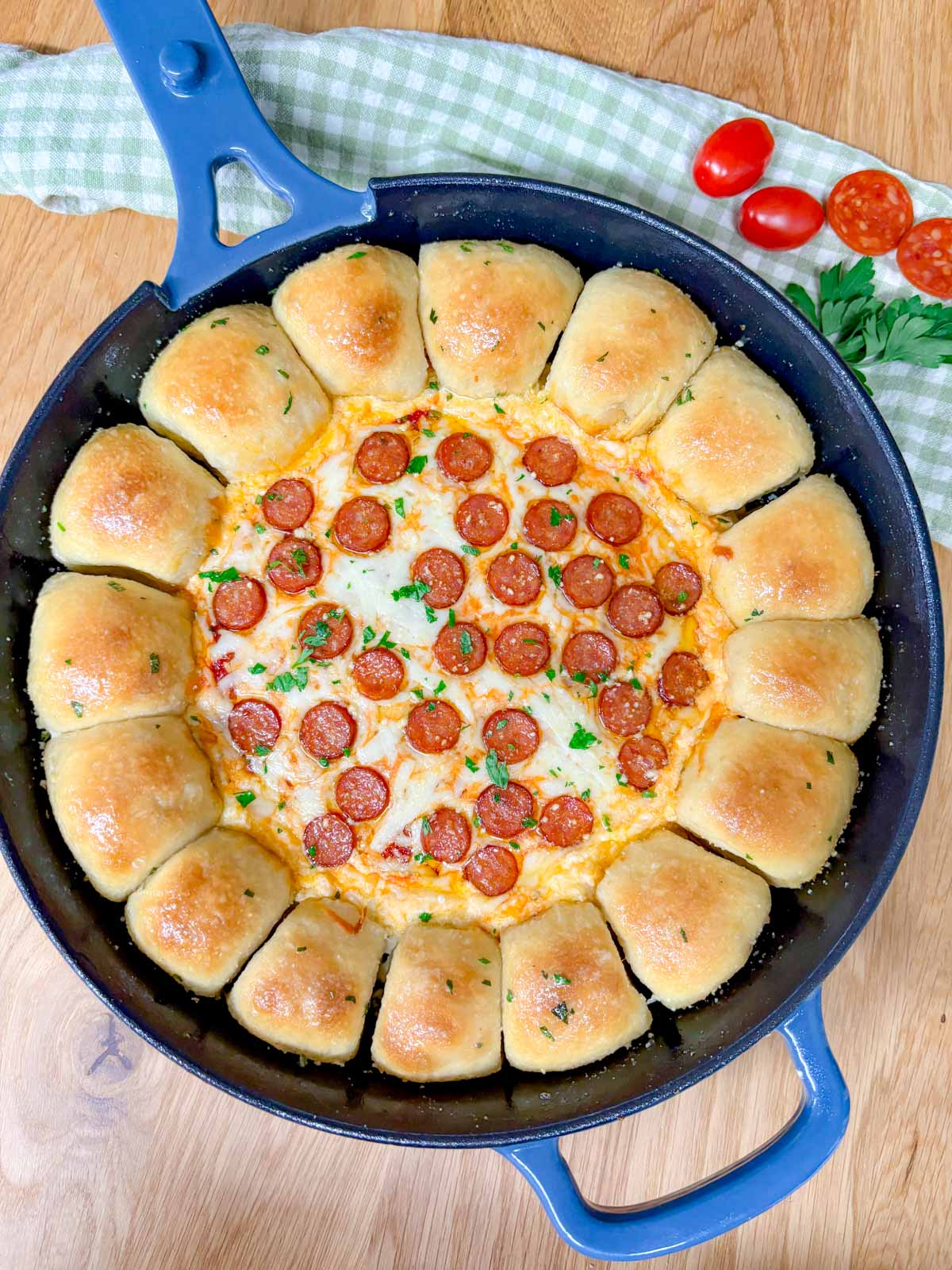 a pizza dip ring with pizza dough balls and a pizza dip in the middle is in a cast iron skillet.